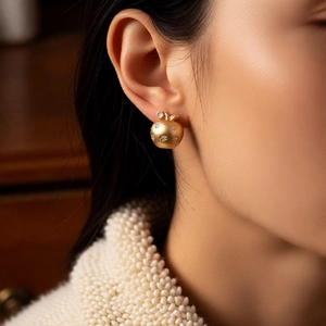 Detail of 18K gold plated apple earrings featuring matte finish and sparkling zircon stones