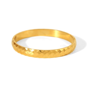 Detail shot of golden stainless steel bangle featuring geometric rhombus cut patterns
