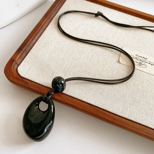 Detail of a black obsidian pendant with smooth finish on a wax rope necklace strap