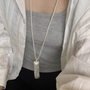 Detail of elegant pearl strand necklace with silver wheat tassel worn by a model