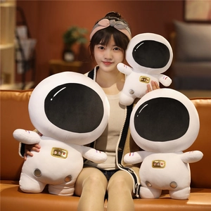 Three sizes of plush astronaut toys with detailed embroidery held by a model in a cozy room