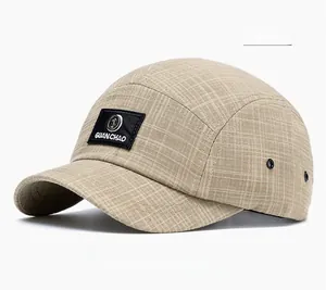Detailed shot of beige plaid five-panel baseball cap showing the logo patch and metal eyelets