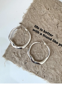 Detail of silver irregular circular earrings on rustic paper with engraved quote