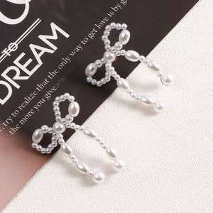 Detailed close-up of handmade pearl bow earrings on a magazine background