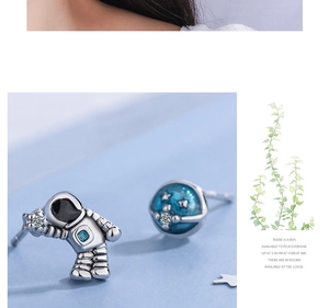 Macro shot of asymmetrical astronaut and blue planet stud earrings with cubic zirconia detail