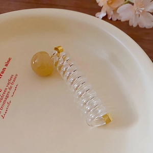Détail d'un élastique spirale transparent avec perle jaune sur un plateau en céramique