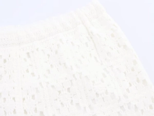 Detail of white crochet knit waist with elastic band and intricate floral cutouts