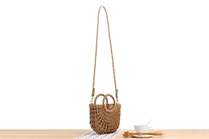 Detail of minimalist paper rope woven semi-circle bag with mesh cutout and shoulder strap