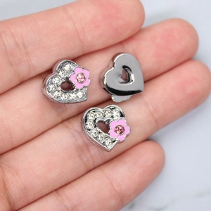 Macro shot of heart-shaped crown charms with rhinestones and pink enamel flowers
