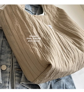 Detailansicht der khakifarbenen Plissee-Tasche mit Stoffstruktur auf Denim-Jacke