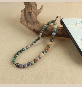 Macro shot of natural stone phone strap with multi-color beads on a zen wood background