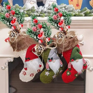 Three knitted Christmas stockings with gnomes, pine needles, and berries on a fireplace