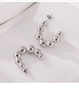 Detail of silver titanium steel C-shaped earrings with gradient beads on a white background