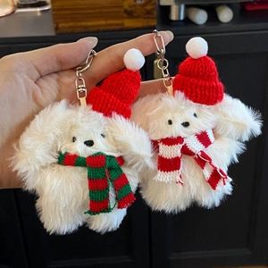 Close-up of white plush bunny keychains with red Christmas hats and striped scarves