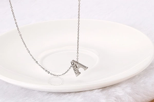 Macro detail of silver-tone letter A pendant featuring five white cubic zirconia stones