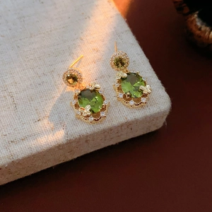 Dettaglio orecchini vintage oro con pietre verdi ovali e zirconi a forma di farfalla