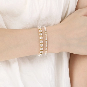 Ensemble élégant de bracelets en perles de verre blanches et dorées porté par un mannequin