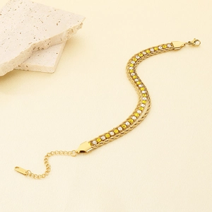 Macro detail of triple-layer gold bracelet with twisted rope chains and zircon inlay
