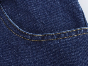 Vue détaillée du tissu denim bleu foncé avec des coutures contrastées orange