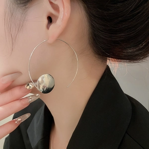Detail of silver geometric hoop earring with hammered disc and crystal on model
