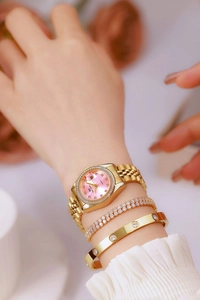 Detail of pink dial women's watch with crystals and gold band on a wrist