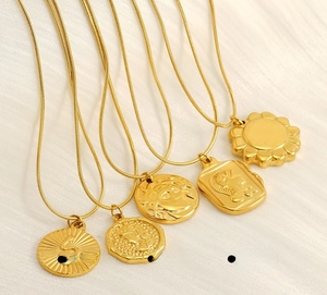Detail of five gold stainless steel necklaces with bohemian coin and snake pendants