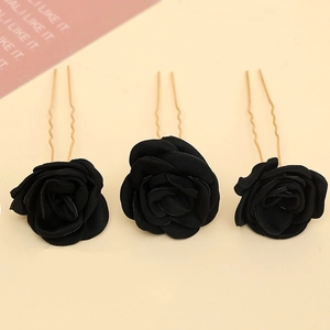 Detailed view of black fabric rose hair pins with golden U-shaped wavy metal prongs