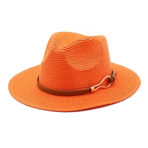 Close-up of orange straw panama hat featuring a brown leather band and golden buckle
