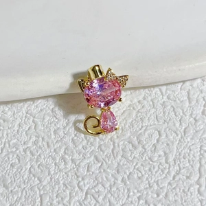 Macro detail of cat-shaped gold-plated pendant with pink gemstones and bow accent