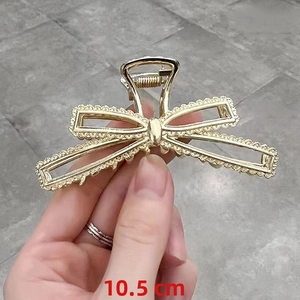 Detailed view of a 10.5cm golden metal hair claw clip with intricate hollow lace texture
