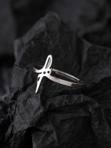 Detail view of silver stainless steel luminous star ring on dark textured paper background
