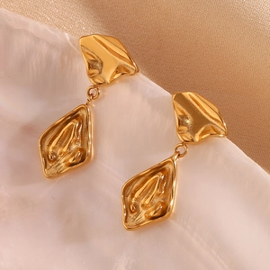 Macro detail of irregular geometric gold-plated earrings on a pearl shell surface