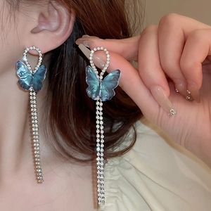 Détail de boucles d'oreilles papillon bleu avec de longues franges en strass