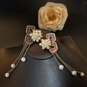 Vintage butterfly pearl tassel earrings with purple crystals on black jewelry display