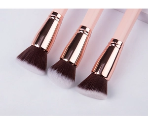 Close-up of three pink makeup brushes with rose gold ferrules and two-tone dense bristles