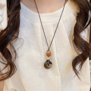 Dettaglio della collana vintage con pietra occhio di tigre a cuore e cordino marrone