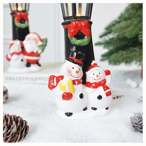 Detail of LED Christmas snowman and Santa Claus street lamp ornament on a snow scene