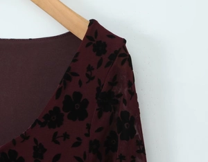 Detail of burgundy mesh dress featuring black floral flocking and plunging V-neckline