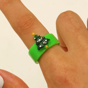 Close-up of a green acrylic Christmas tree ring worn on hand for festive holiday jewelry