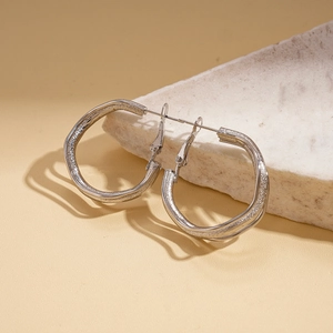 Macro shot of silver textured triple-layered hoop earrings on a decorative stone