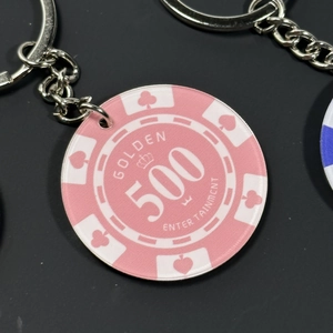 Close-up of pink 500 poker chip keychain with card suits and crown design detail