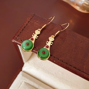 Detail view of gold-plated Pipa lotus earrings with green agate on dark leather