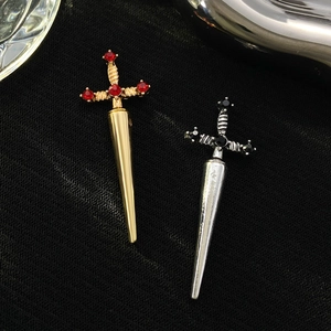 Detailed close-up of gothic sword brooches with red and black crystals on black fabric