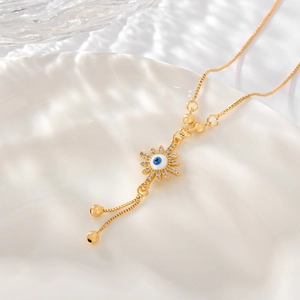 Macro shot of evil eye pendant with cubic zirconia accents and gold bead tassels