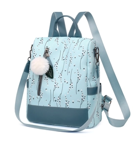 Detailed side view of light blue floral backpack with plush ball charm and side pockets