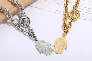 Detail of silver and gold Hamsa hand necklaces with OT toggle clasp on artistic background
