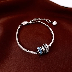 Macro view of silver bangle with blue zircon rotating beads on red silk background