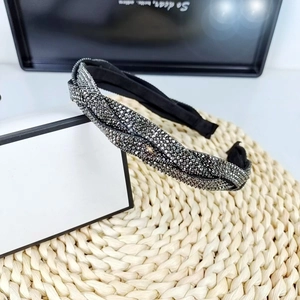 Detailed view of black braided headband with sparkling rhinestones on a woven mat