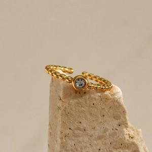 Detail of 18K gold plated beaded open ring with central round zircon on natural stone
