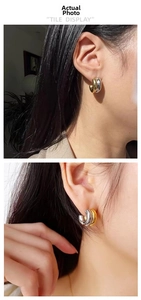 Detailed view of chunky C-shaped two-tone gold and silver stainless steel hoop earrings
